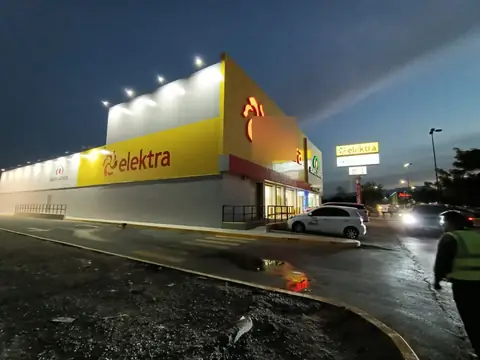 Fachada Elektra al anochecer, con personal en obra