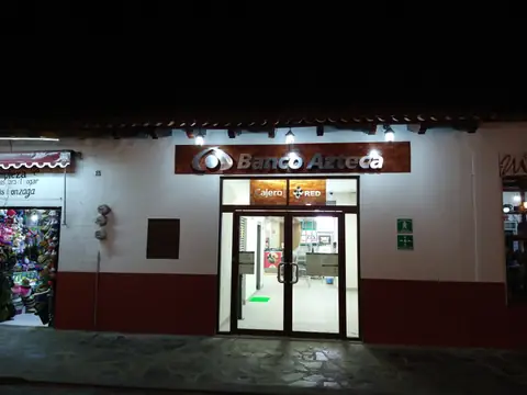 Fachada de noche con rótulo Banco Azteca en construcción de estilo colonial