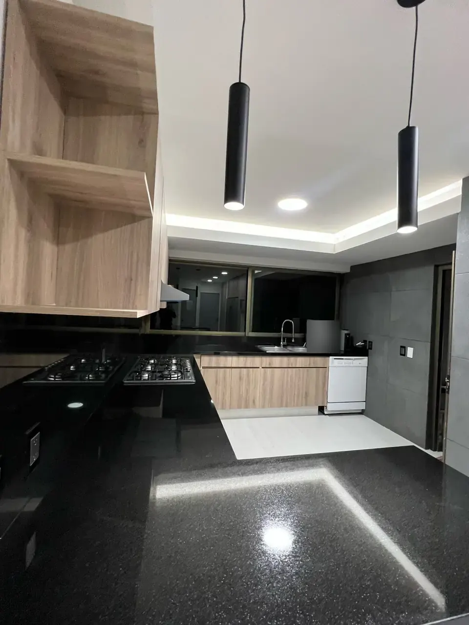 Cocina terminada: parrilla y cubierta de granito negro con luz indirecta