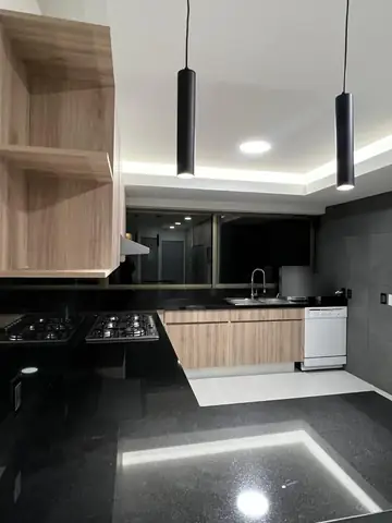 Cocina terminada: repisas de madera, luminarias colgantes y piso con luz indirecta